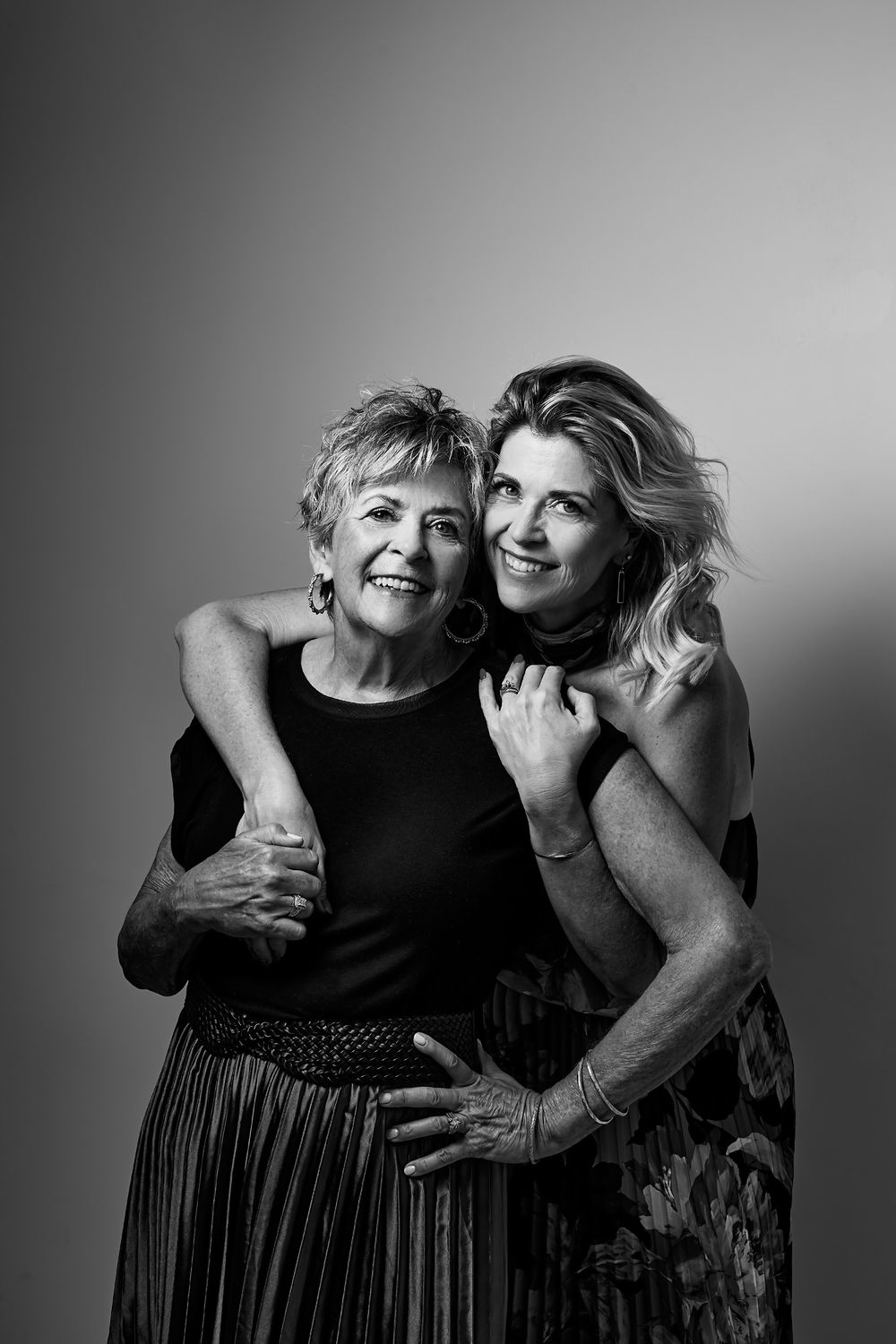 Black and white photo series showing two women embracing and laughing together.
