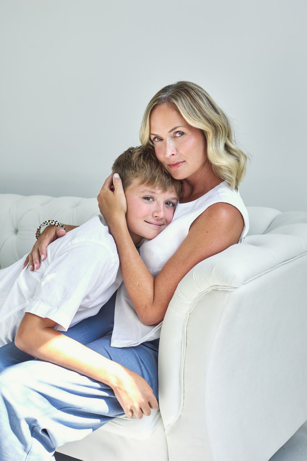 Intimate portrait series of mother and child relaxing together on white couch.
