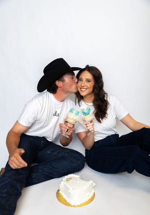 A couple in white t-shirts and jeans share ice cream cones while lying on a white background in a photo series.