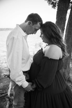 A romantic black and white photo series showing a couple embracing under trees by the water.
