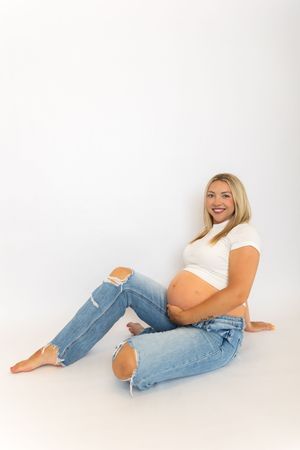 Person in casual white top and blue jeans lying on white background in relaxed poses.