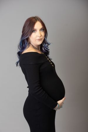 Model wearing black sweater with blue-tinted hair poses against grey backdrop in artistic portrait series.