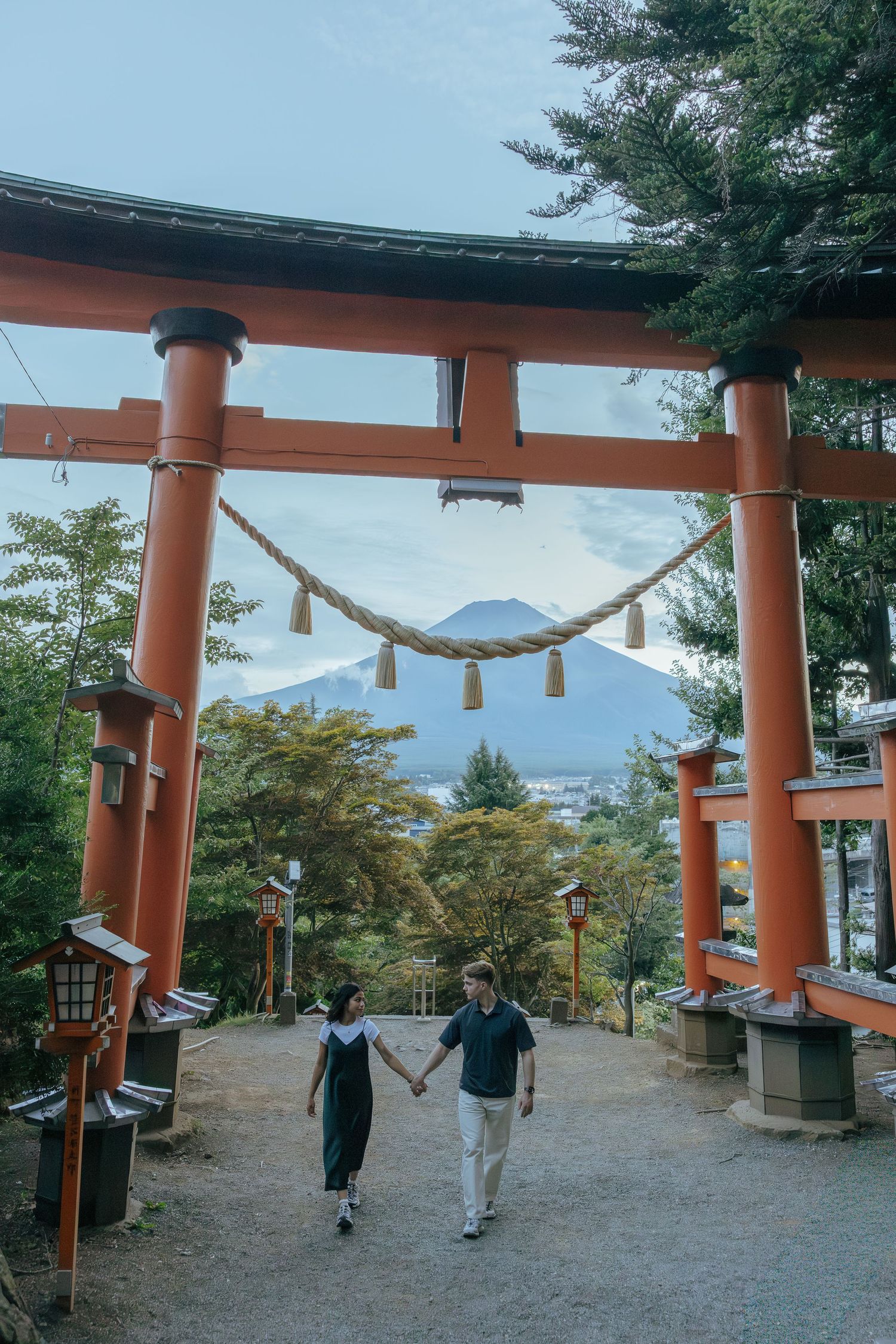 Engagement photoshoot around traditional orange torii gate of Chureito Pagoda with Mount Fuji visible in the background.