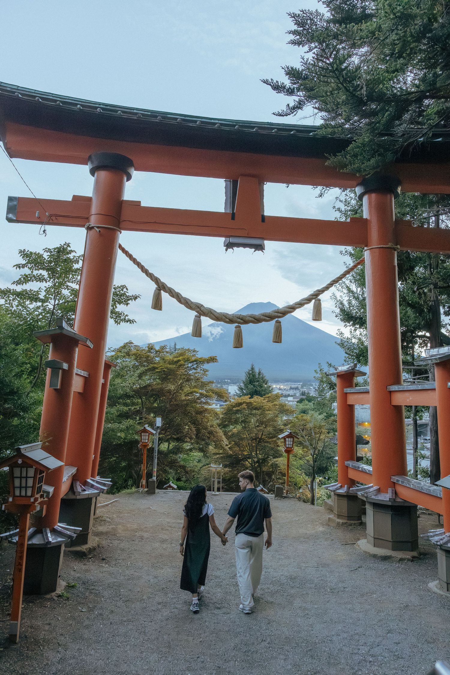 Engagement photoshoot around traditional orange torii gate of Chureito Pagoda with Mount Fuji visible in the background.