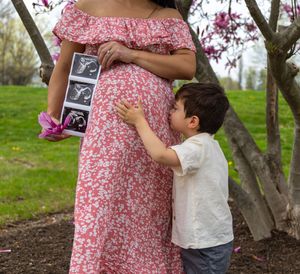 A series of photos showing a young child hugging someone in a pink floral dress under blooming cherry blossom trees.