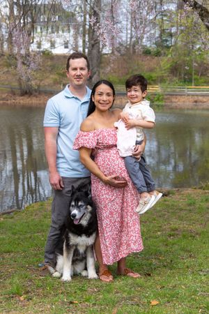 Family with their husky mix dog enjoying a sunny afternoon by a peaceful lake.