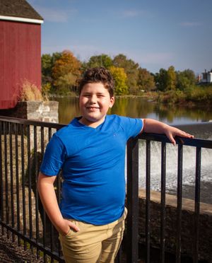A scenic view of a lake with fall foliage and a red building visible in the background.