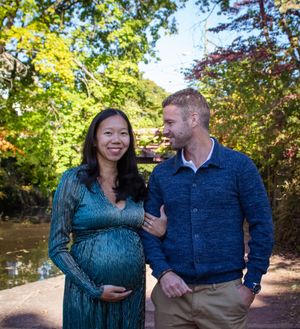 A couple shares joyful moments together while walking through a sunlit autumn park in coordinated blue outfits.