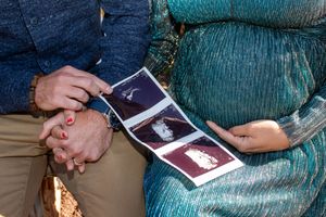 A couple looks at ultrasound photos together while sitting outdoors on a fall day.