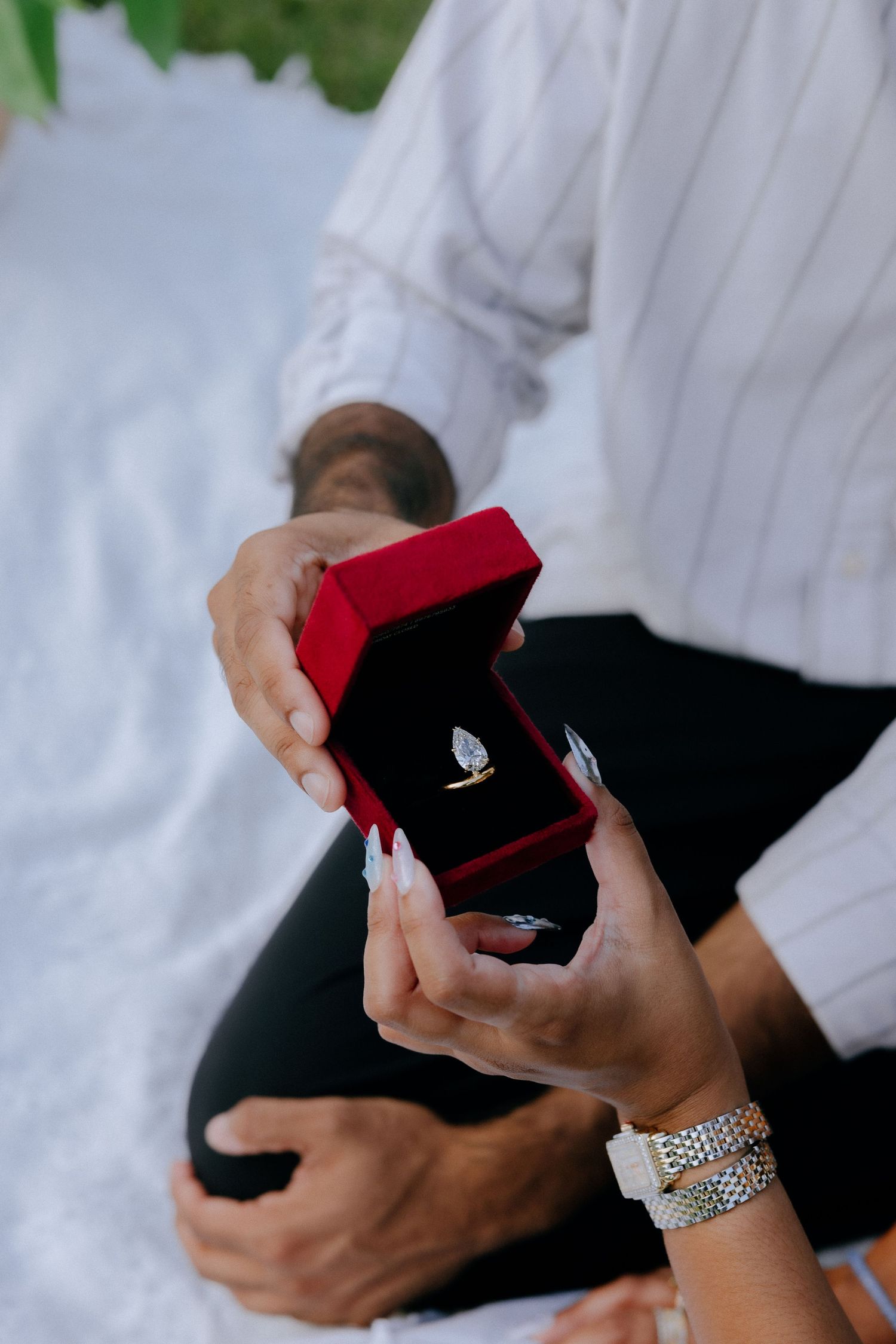 Close-up sequence of hands holding and opening a small red velvet ring box.