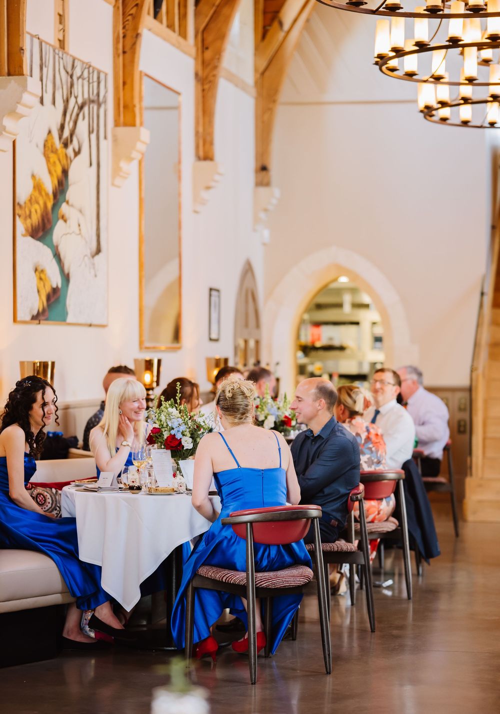 Guests seated at round tables during an elegant indoor reception with ornate columns and chandeliers. Relaxed Dorset Wedding photographer