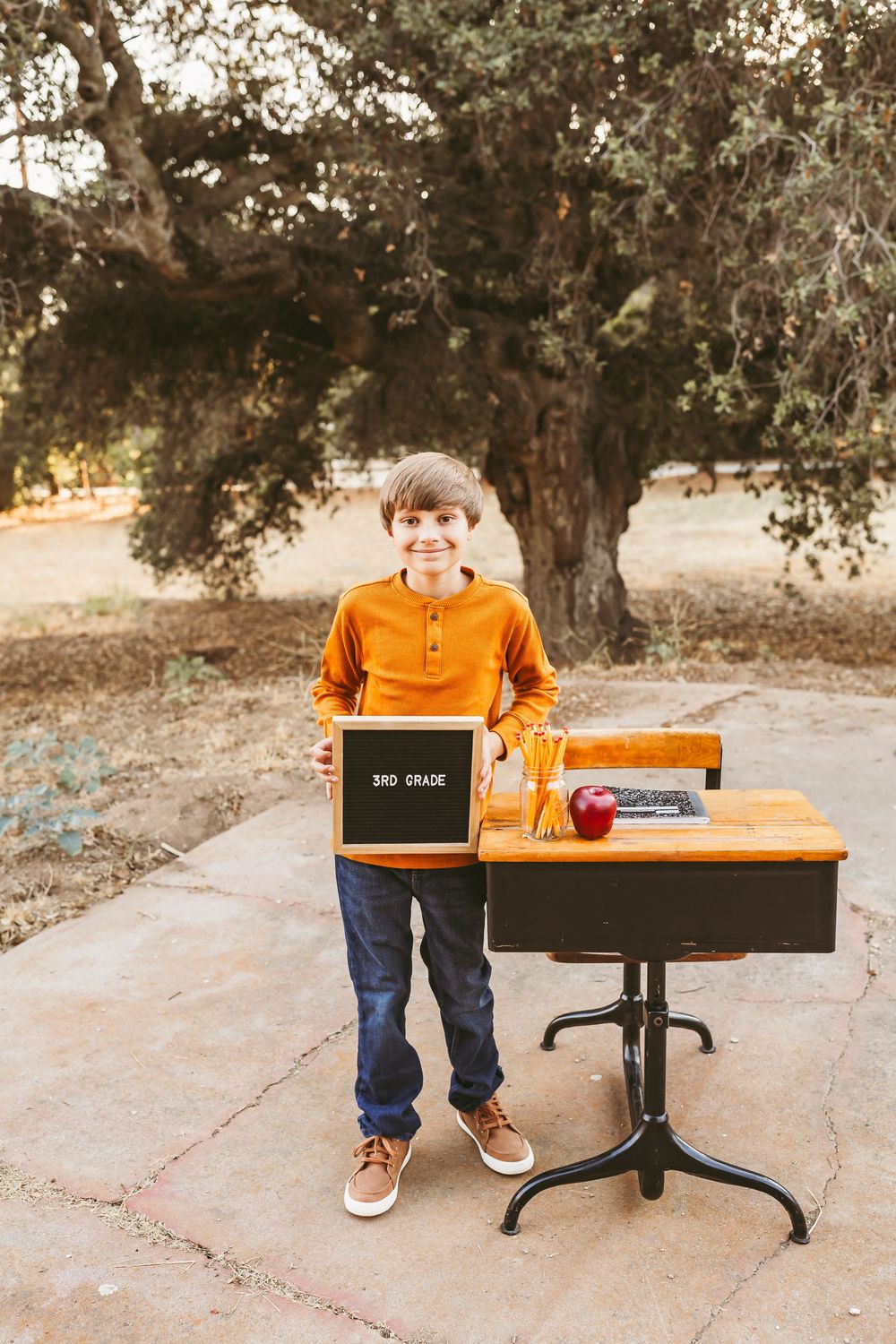 A series of five photos showing a child in an orange shirt sitting at a modern black desk in an outdoor setting.
