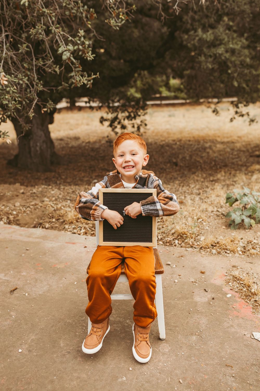A series of photos showing a young child sitting in a white chair outdoors during autumn with orange pants and sneakers.