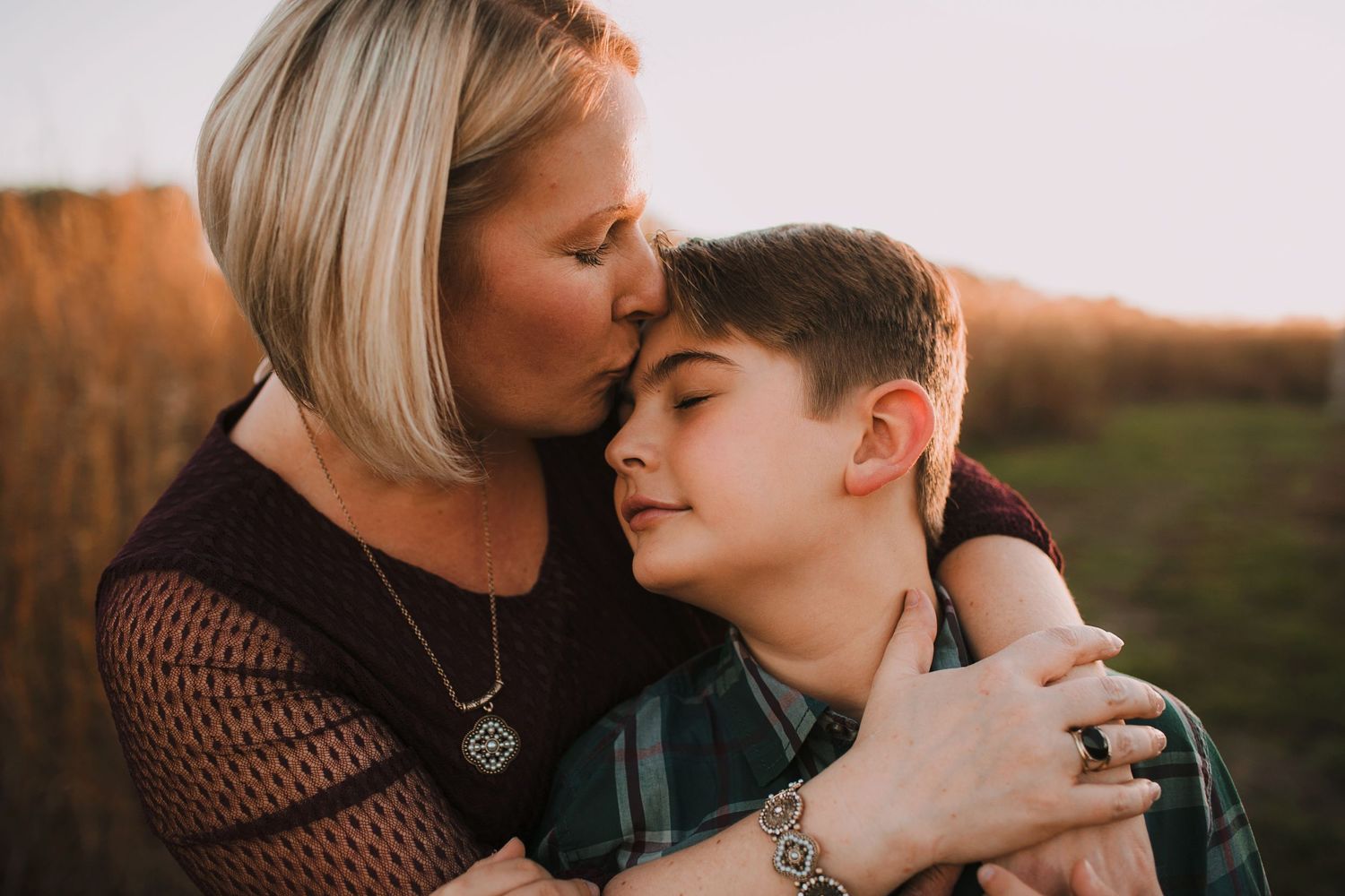 Mother and son hugging in field during fall family photo session in Springfield MO.