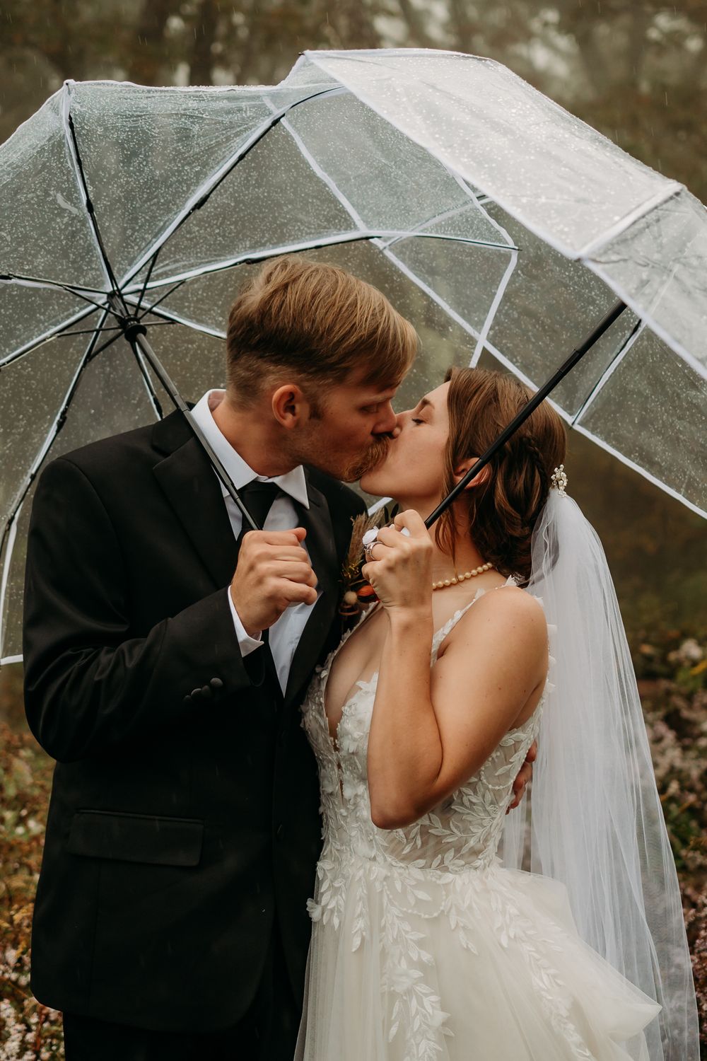 Couple kissing while holding umbrellas.