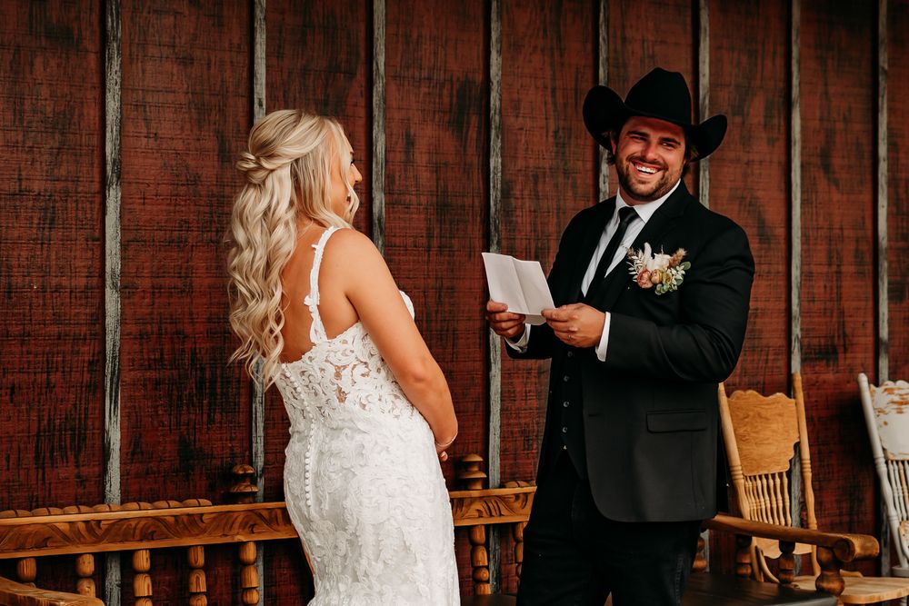 Wedding ceremony moment as couple exchanges vows in rustic barn setting.