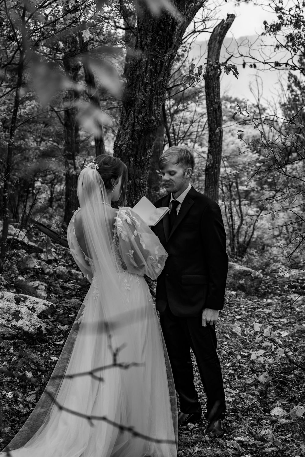 A black and white wedding ceremony photo captured in a forest setting.