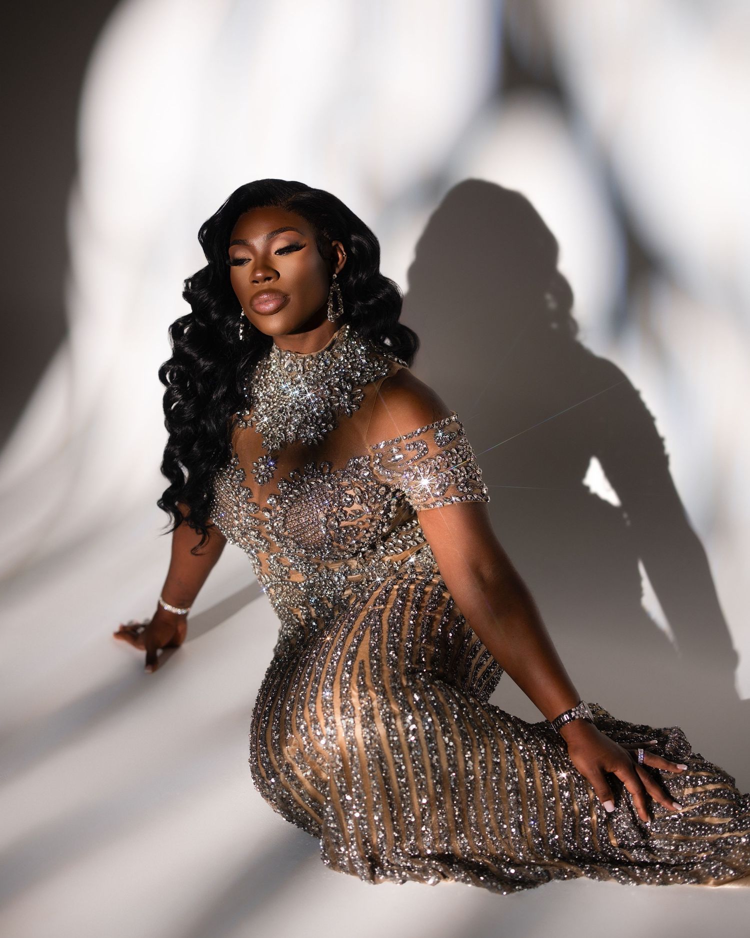 A glamorous silver sequin dress sparkles against a dark backdrop with disco balls and silver balloons creating a festive atmosphere.