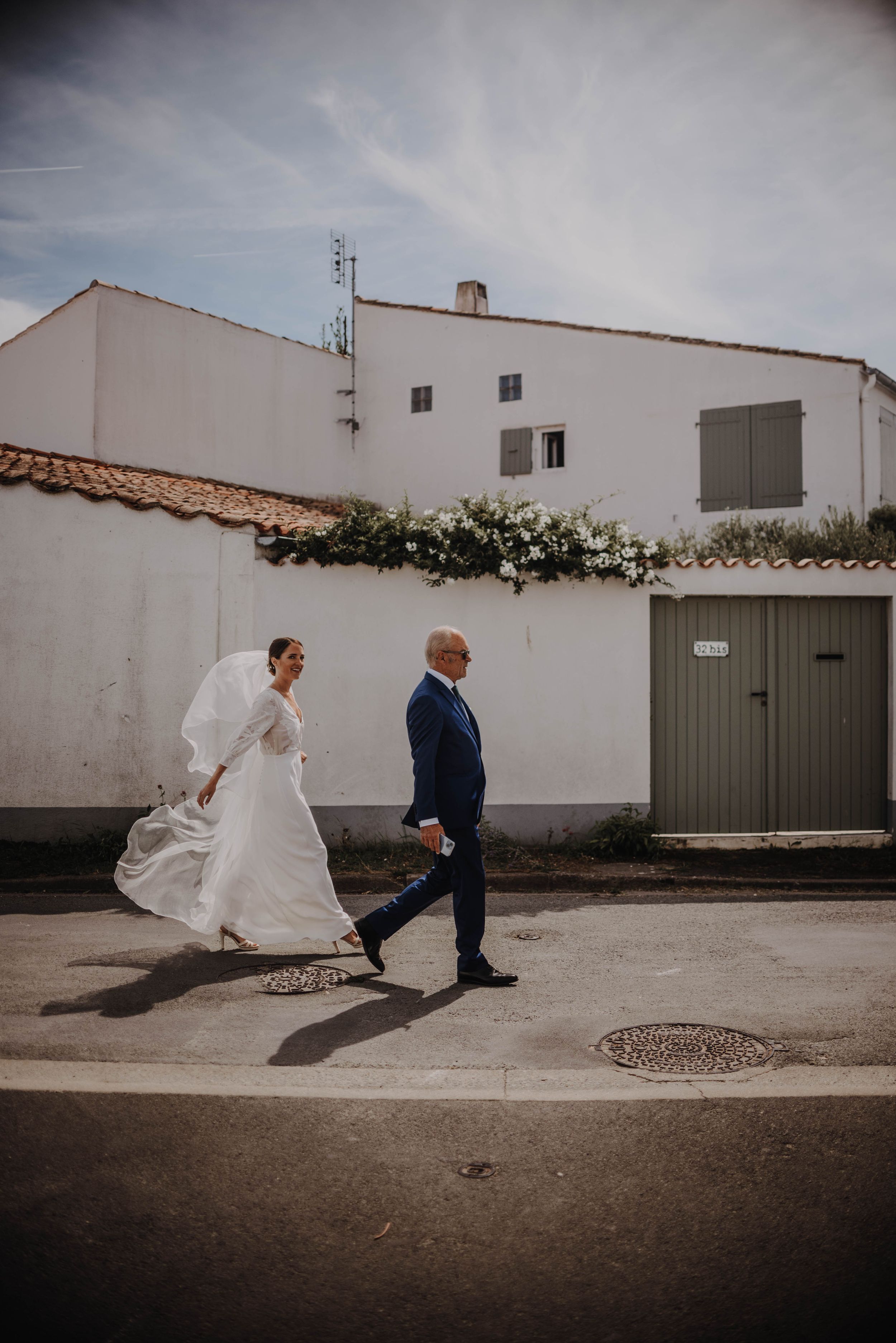 A sequence of artistic wedding photos showing a couple walking along a white wall in a minimalist urban setting.