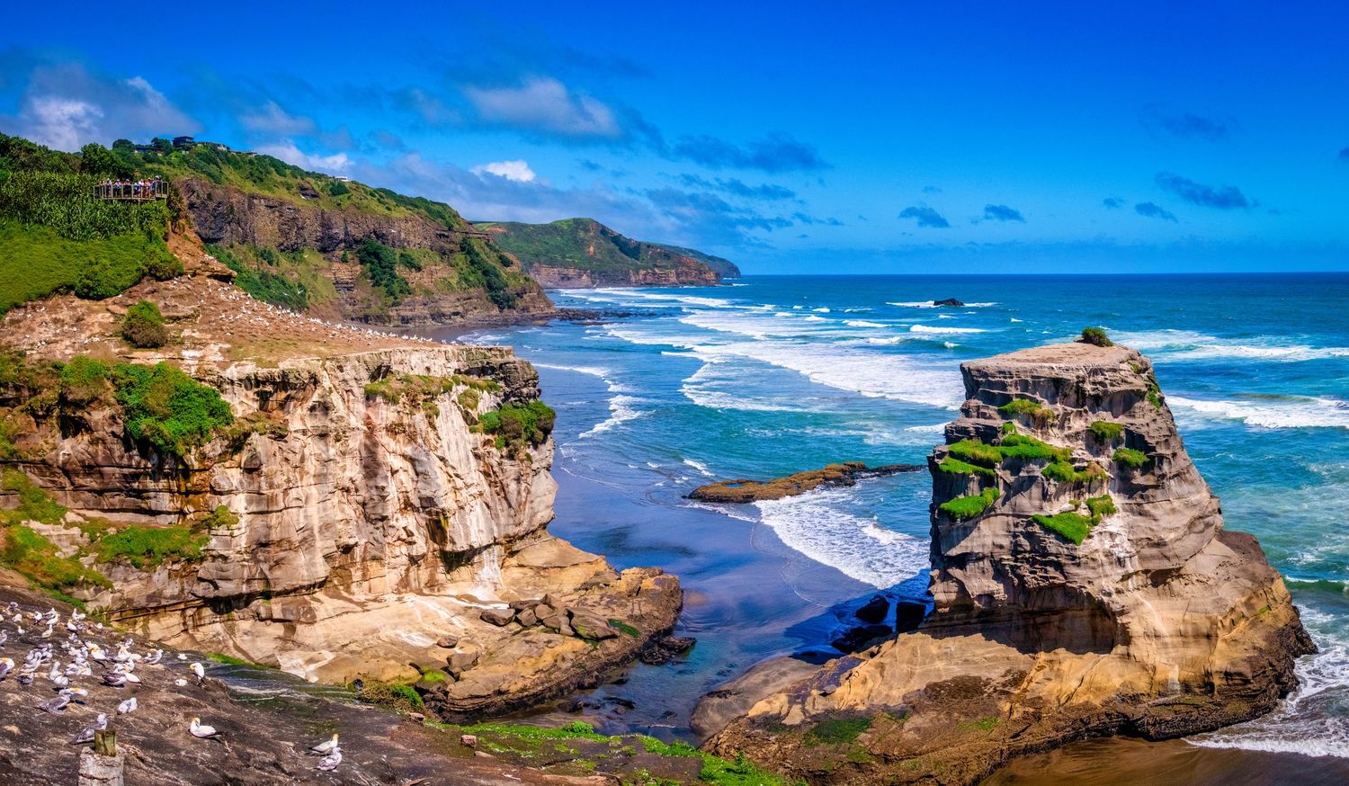 Panoramic view of rugged Oregon coastline with dramatic cliffs, crashing waves and sandy beaches under blue skies.