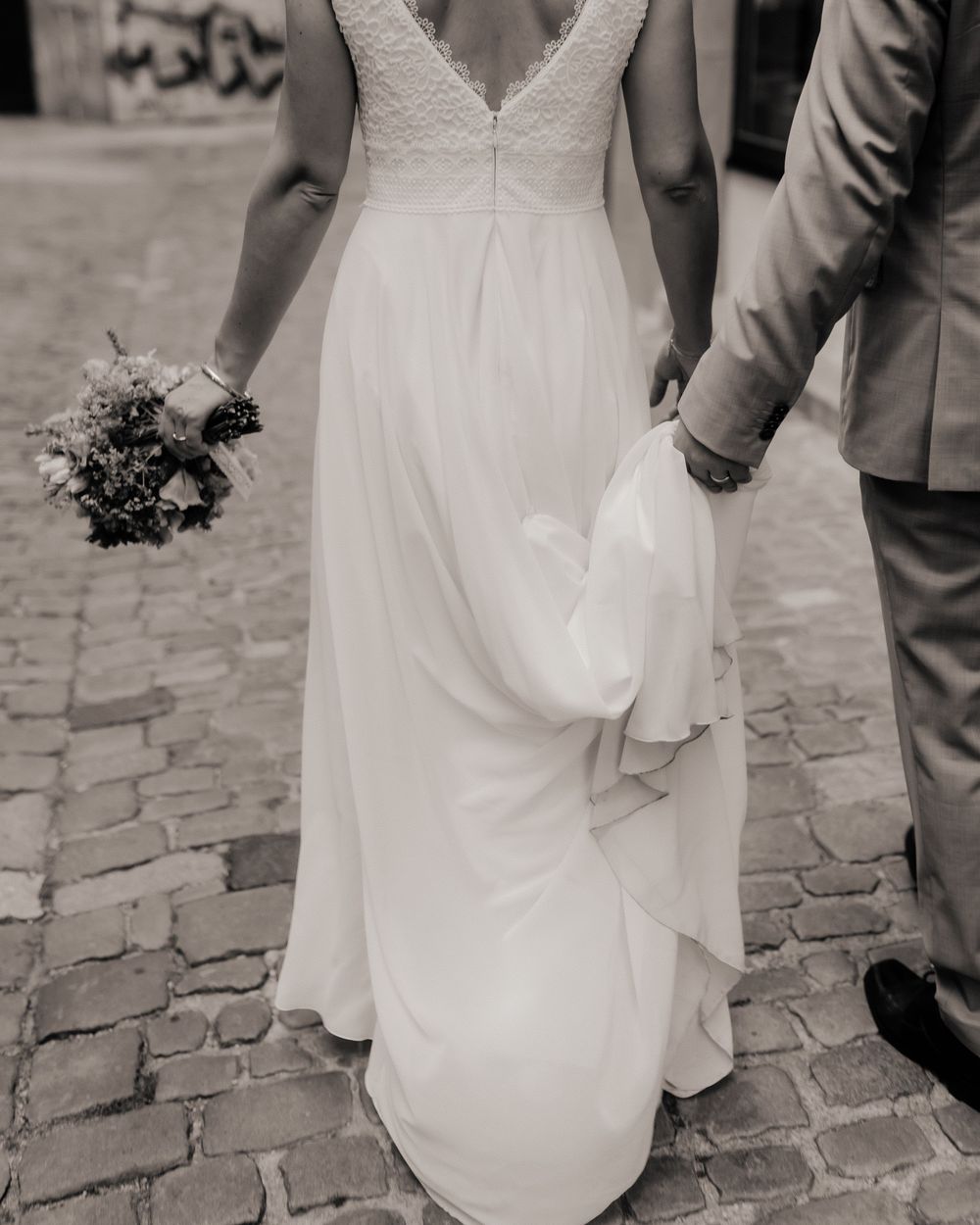 Black and white image series showing close-up details of a wedding dress and shoes on cobblestone pavement.