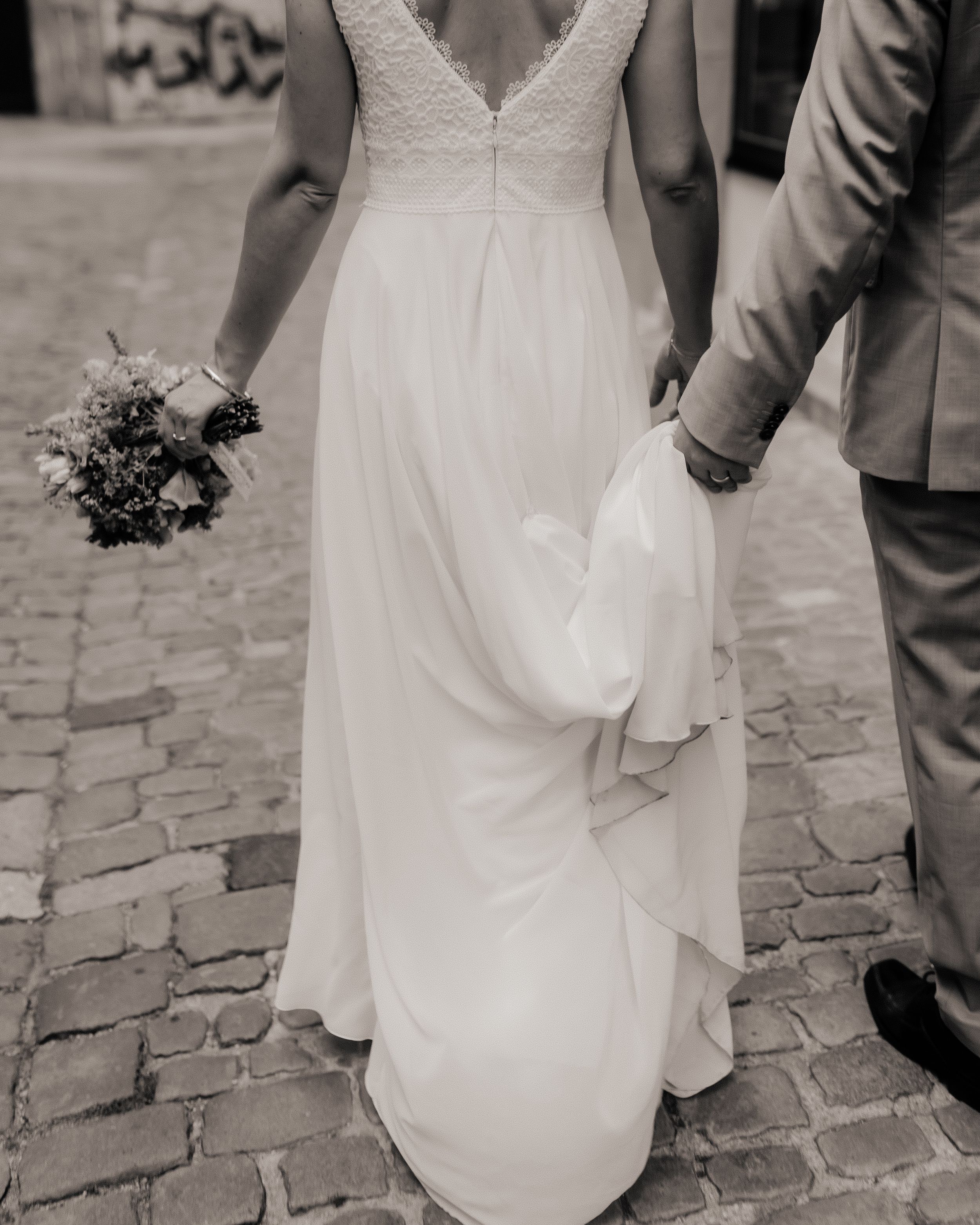 Black and white image series showing close-up details of a wedding dress and shoes on cobblestone pavement.