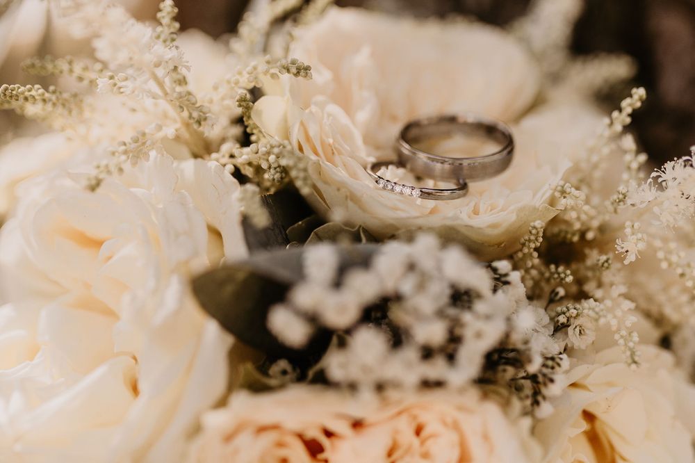 Delicate white and blush floral wedding bouquet with baby's breath and roses arranged on a light surface.
