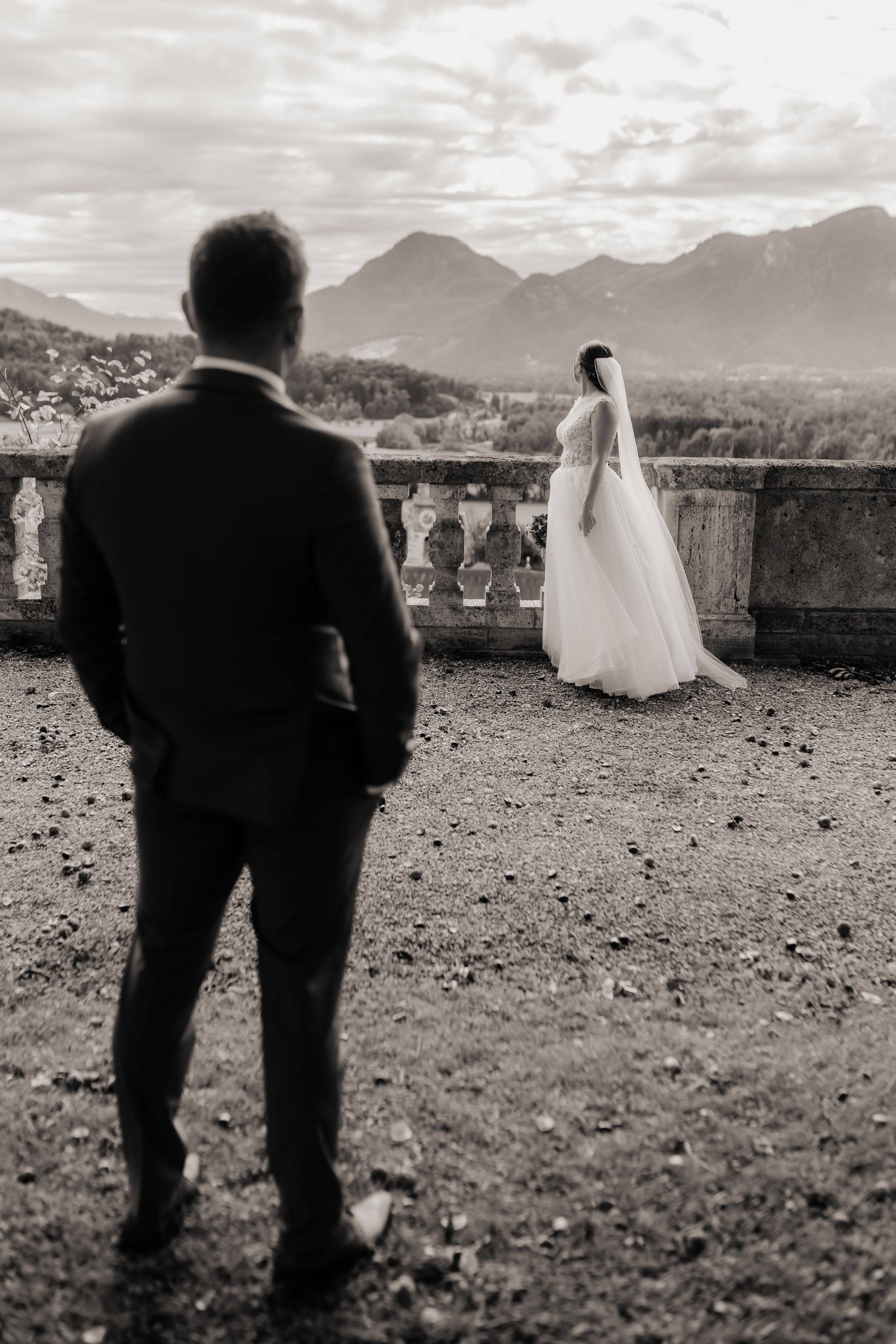 Black and white wedding photo series showing a couple on a scenic mountain overlook with dramatic cloudy skies.