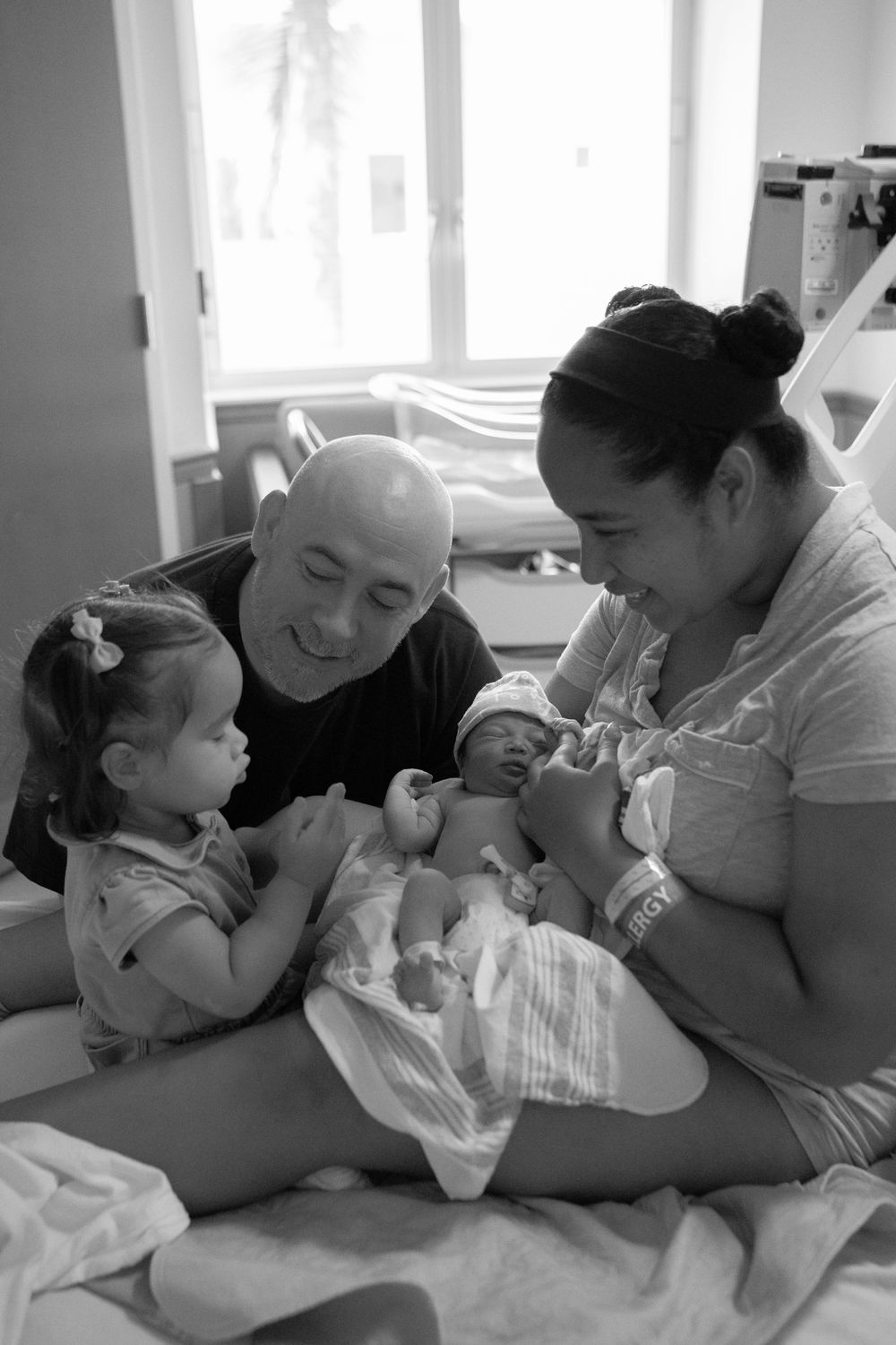 A series of black and white photos showing tender moments between a parent and newborn baby.