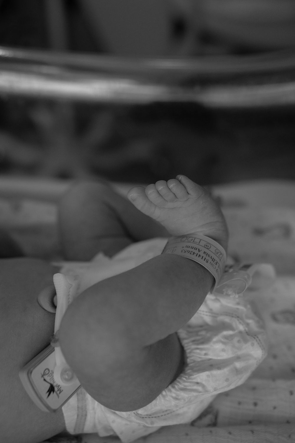 Black and white image of a newborn baby wrapped in blankets in a medical setting.