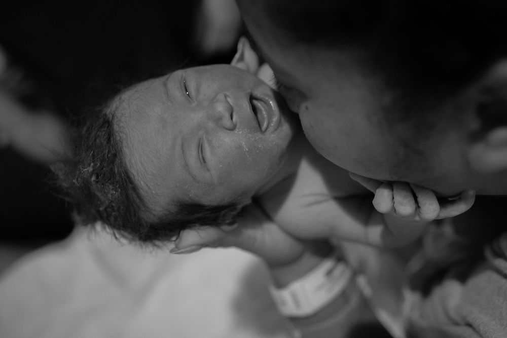 Close-up black and white photos capturing intimate bonding moments with a newborn.