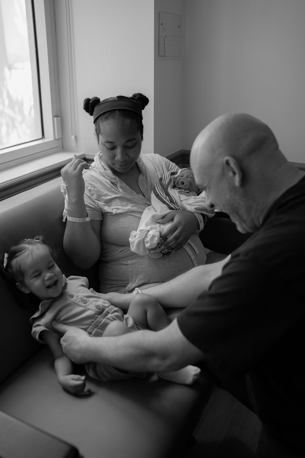 Black and white photos of parents sharing quiet moments with their newborn in a hospital room.
