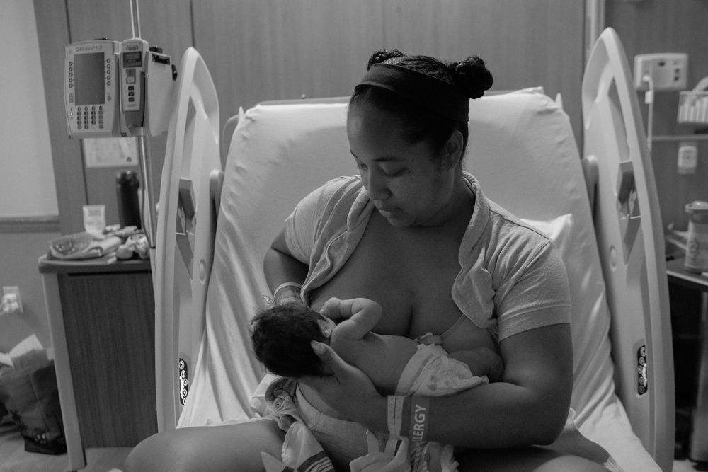 Black and white photo of a tender moment between parent and newborn in a hospital room.