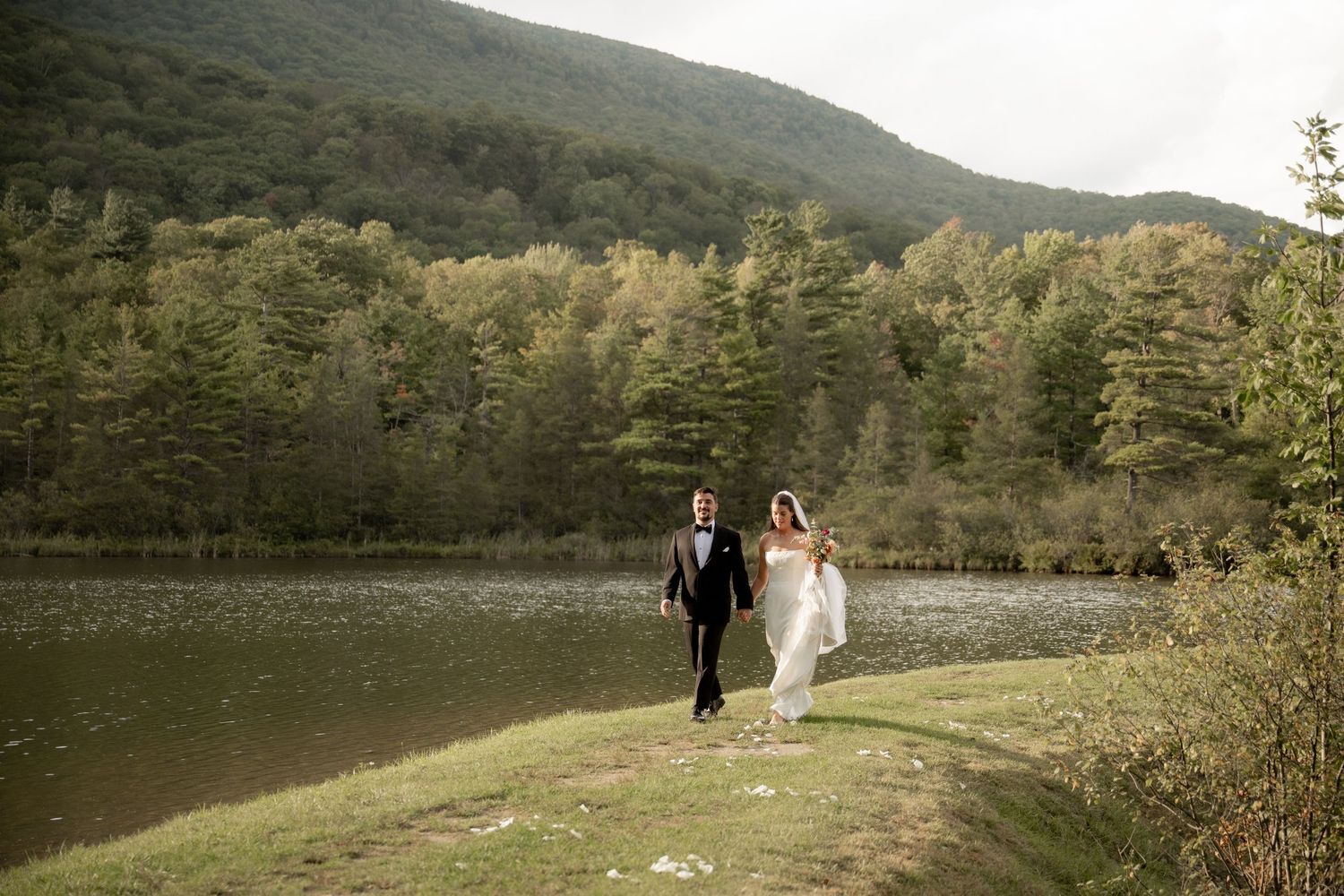A couple stands in a scenic mountain landscape during a photo session in the lush green wilderness.