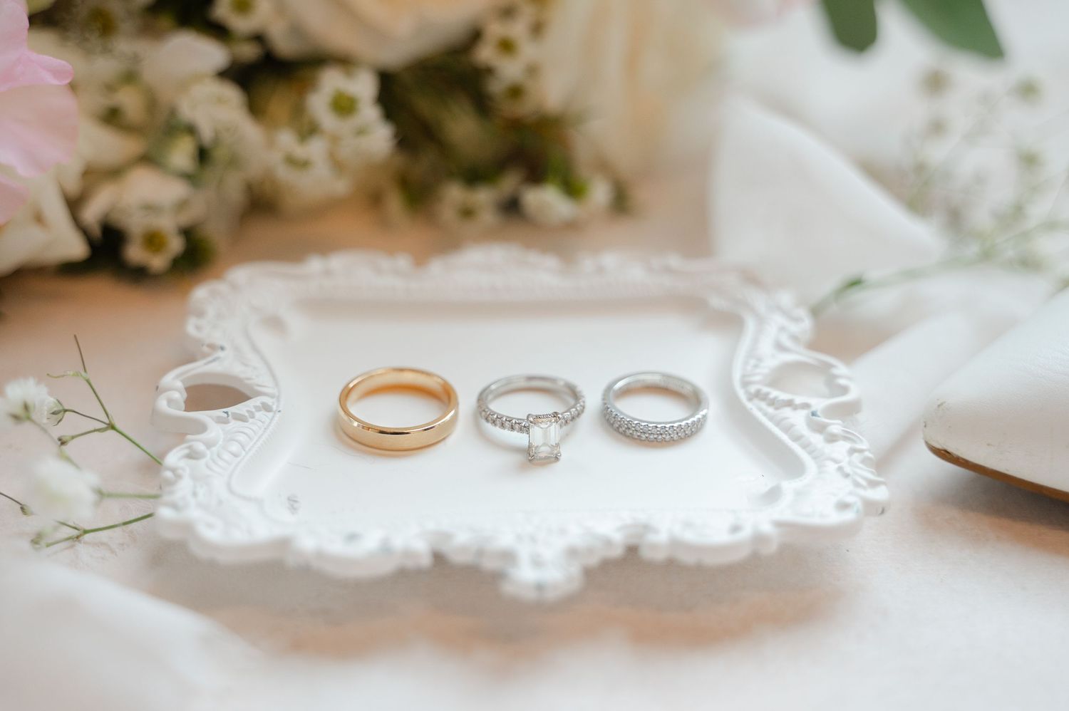 Wedding rings and delicate lace details create an elegant bridal setting on a light surface.