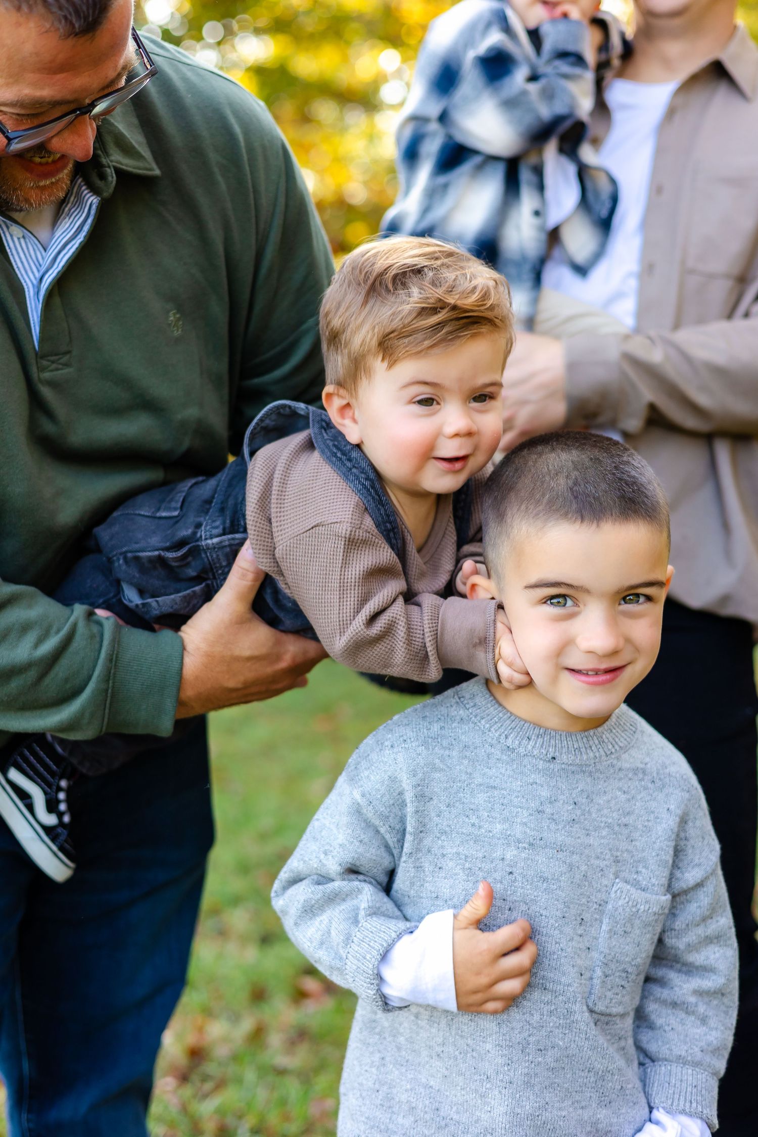 A family enjoys quality time together outdoors on a sunny autumn day with golden foliage in the background.