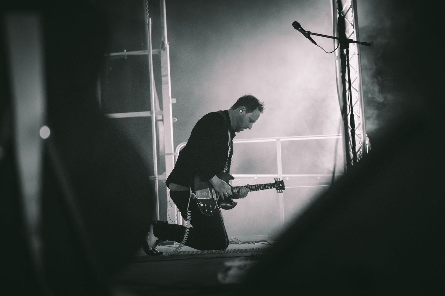 A black and white photo series showing someone playing guitar in moody window lighting.