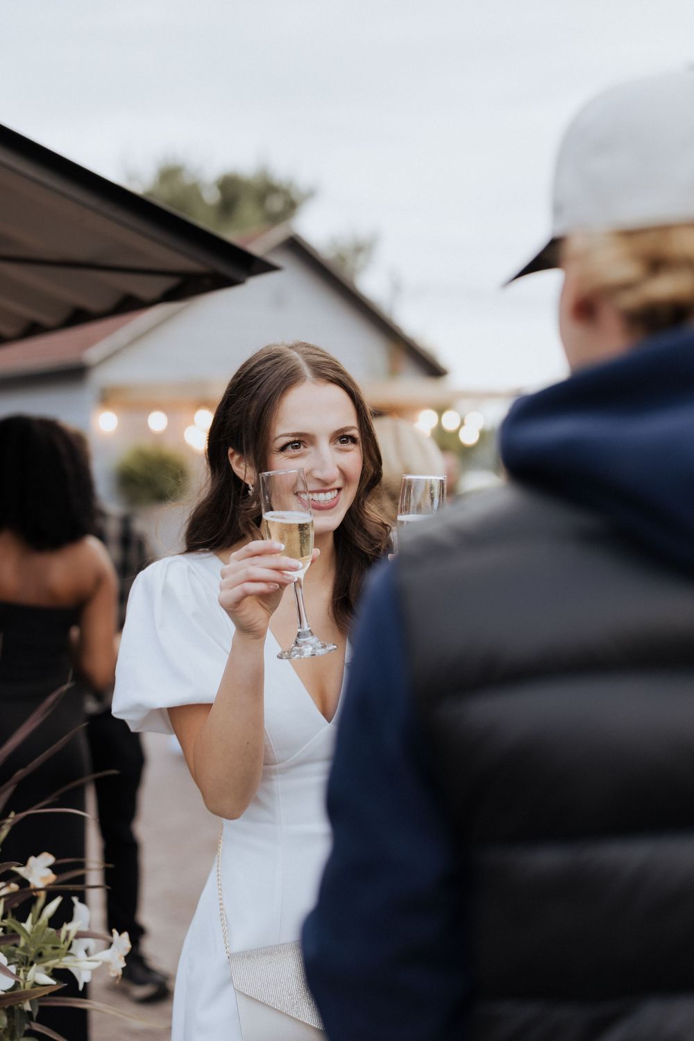 Bride cheers with champagne glass during intimate engagement party turned surprise wedding, surprising guests, Moncton photographer NB