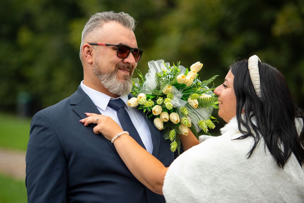 A bride and groom share a tender moment outdoors while the bride holds a yellow and white bouquet.