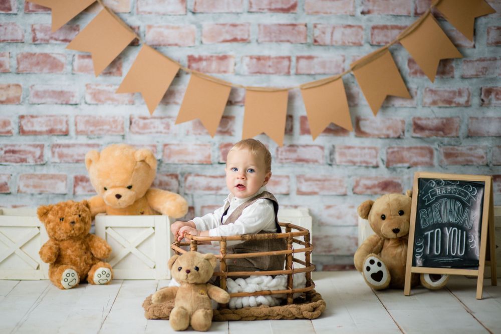 Vintage birthday scene with teddy bears, brick wall background, and rustic wooden decorations.
