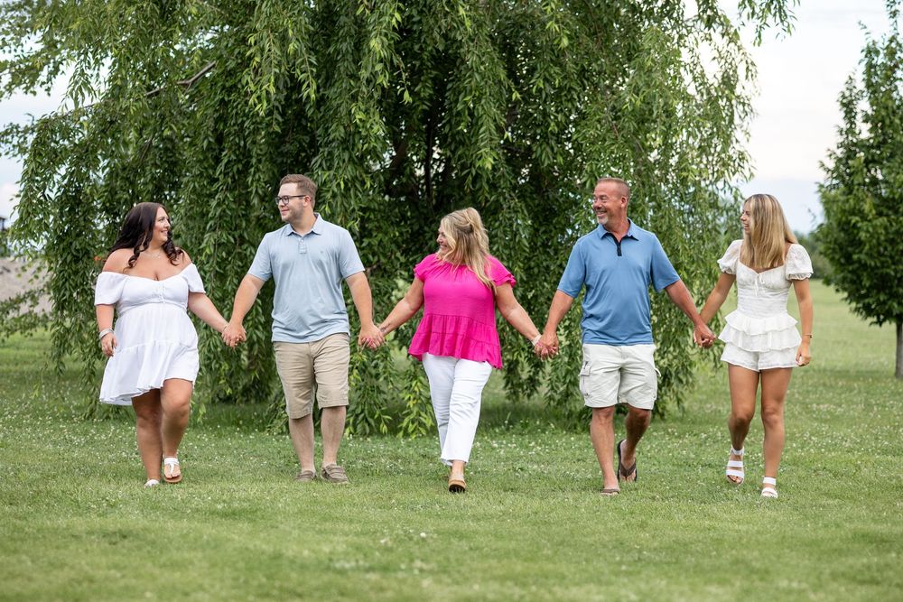 Springfield, IL Photographer captures a family holds hands and walks together during a photo session at Centennial Park in Springfield, IL