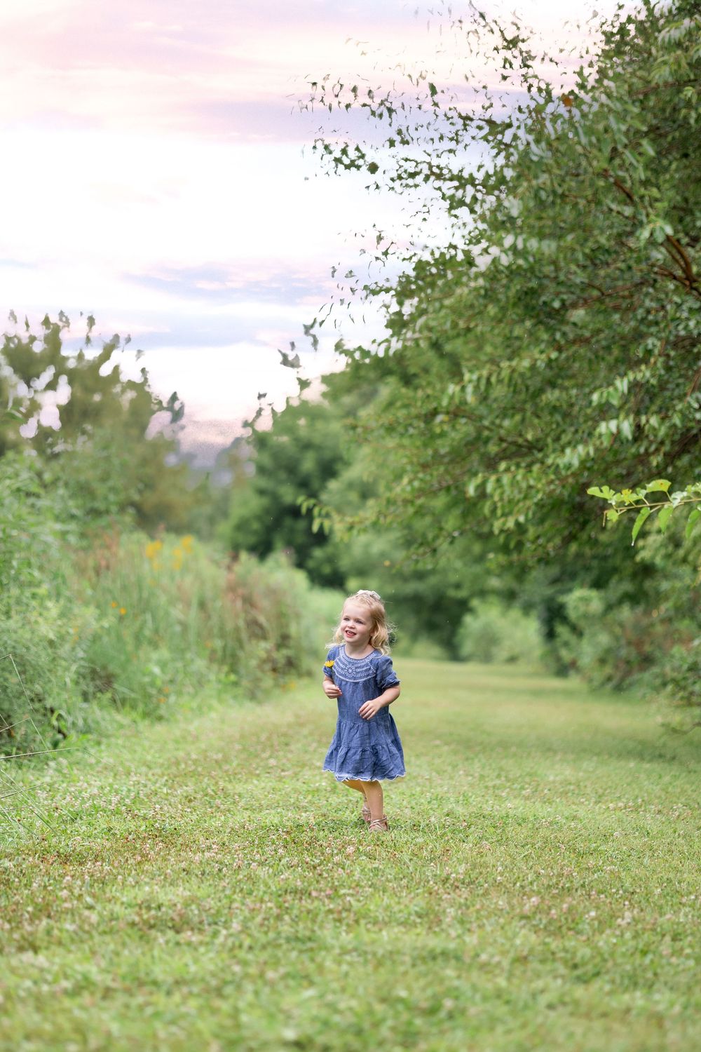 A girl smiles and walks in open grass during a photo session at Centennial Park in Springfield, IL