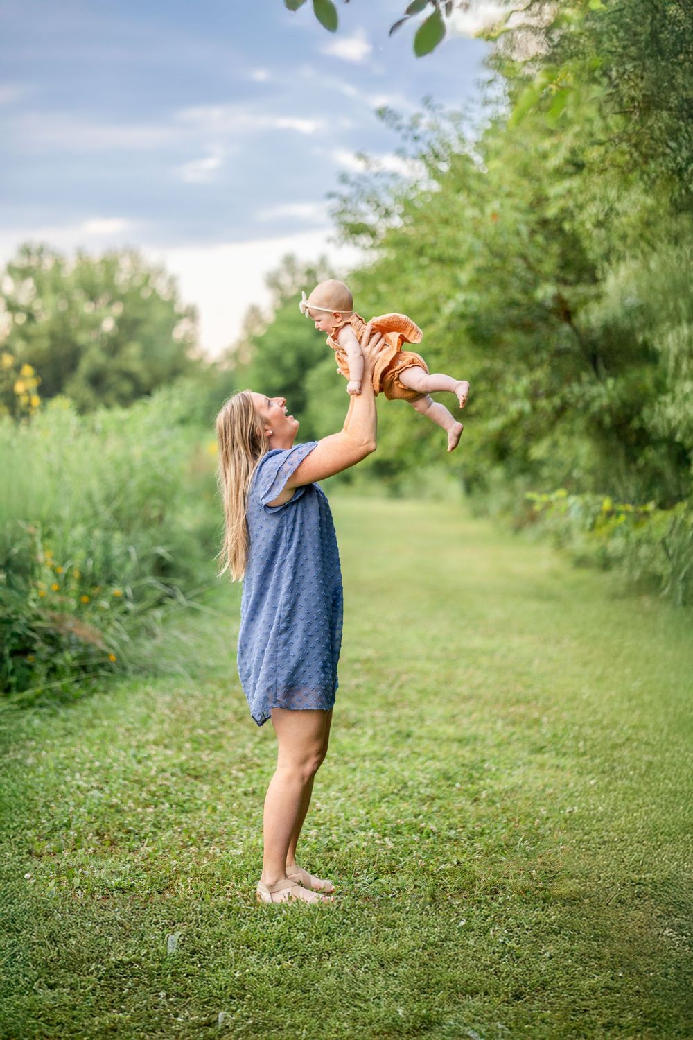 A mom holds her baby in the air during a photo session at Centennial Park in Springfield, IL