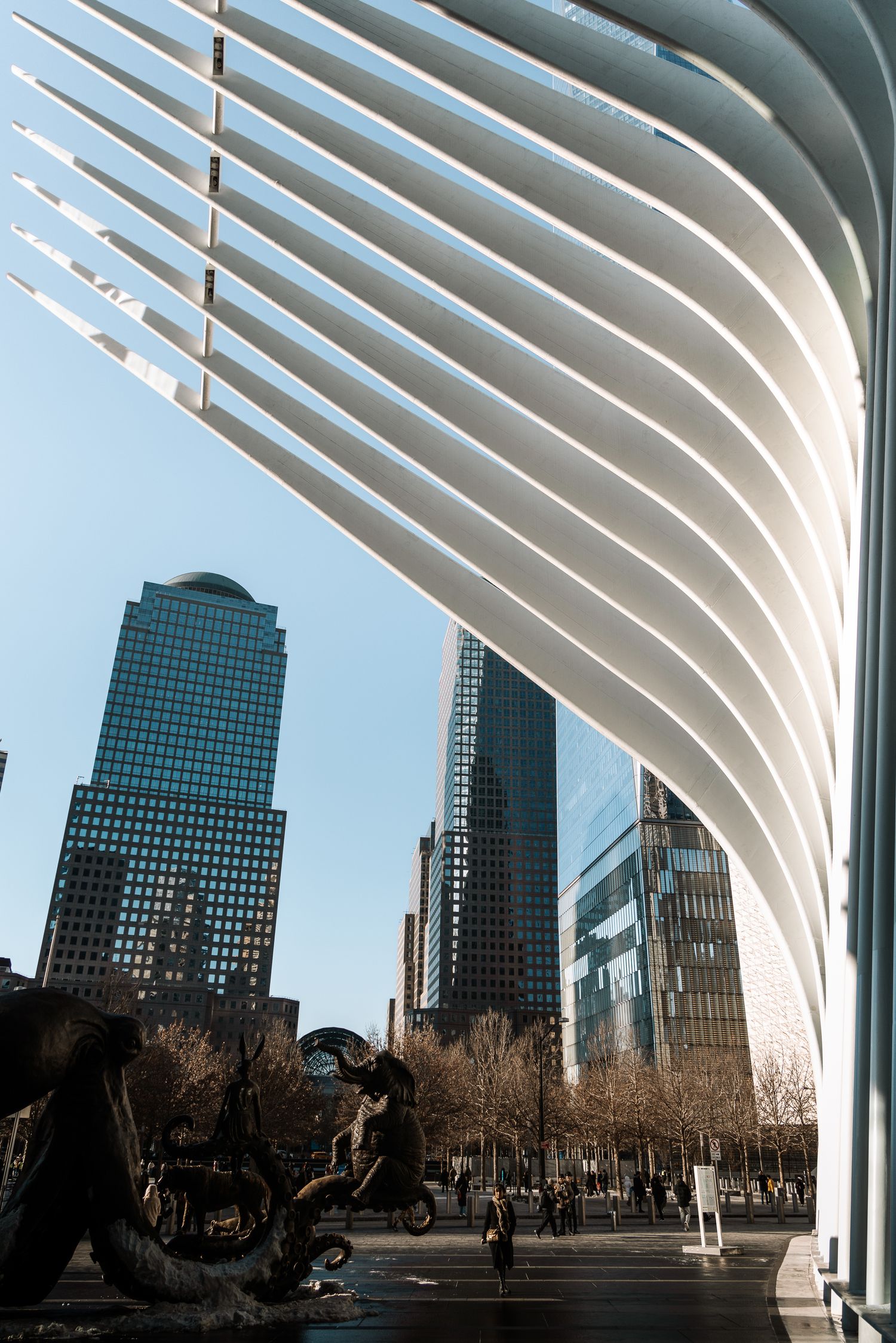 Curved white architectural ribs frame city skyscrapers against blue sky.