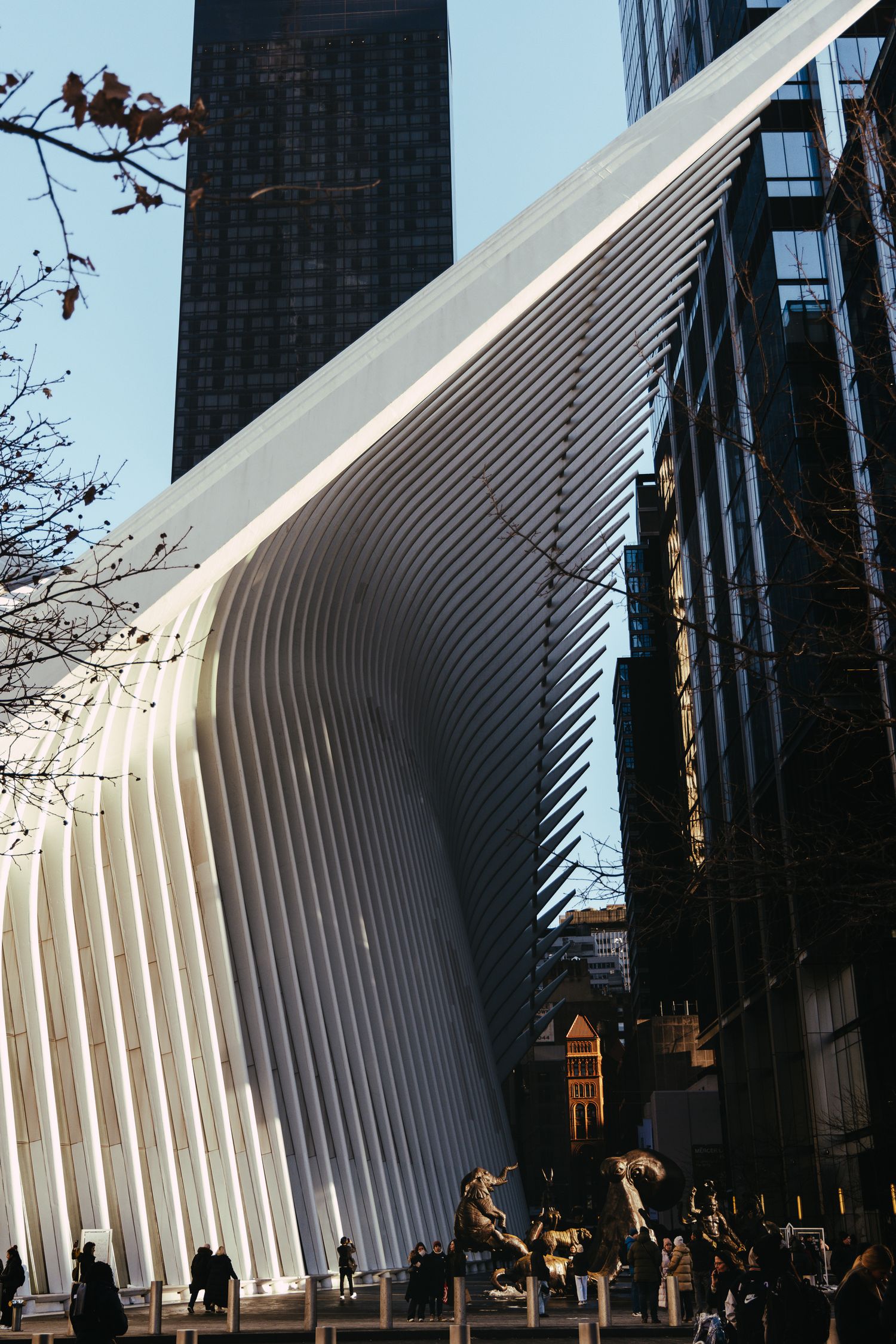 Geometric white architectural structure with ribbed walls casting dramatic shadows in downtown setting.