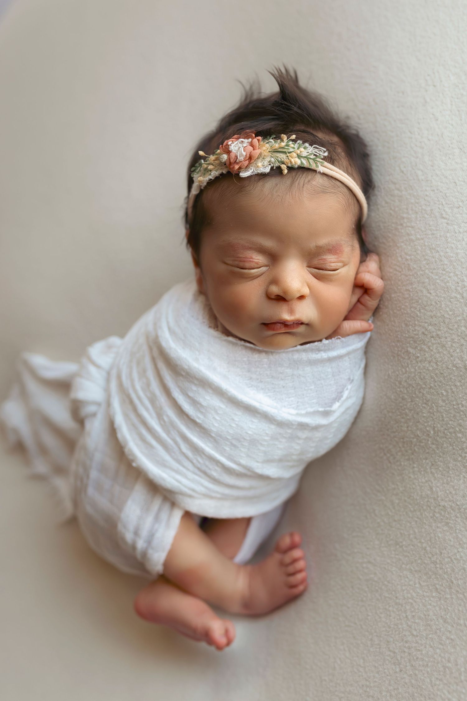bebe envuelta en una tela blanca que estira posando de lado bebes en ponce Fotografa infantil