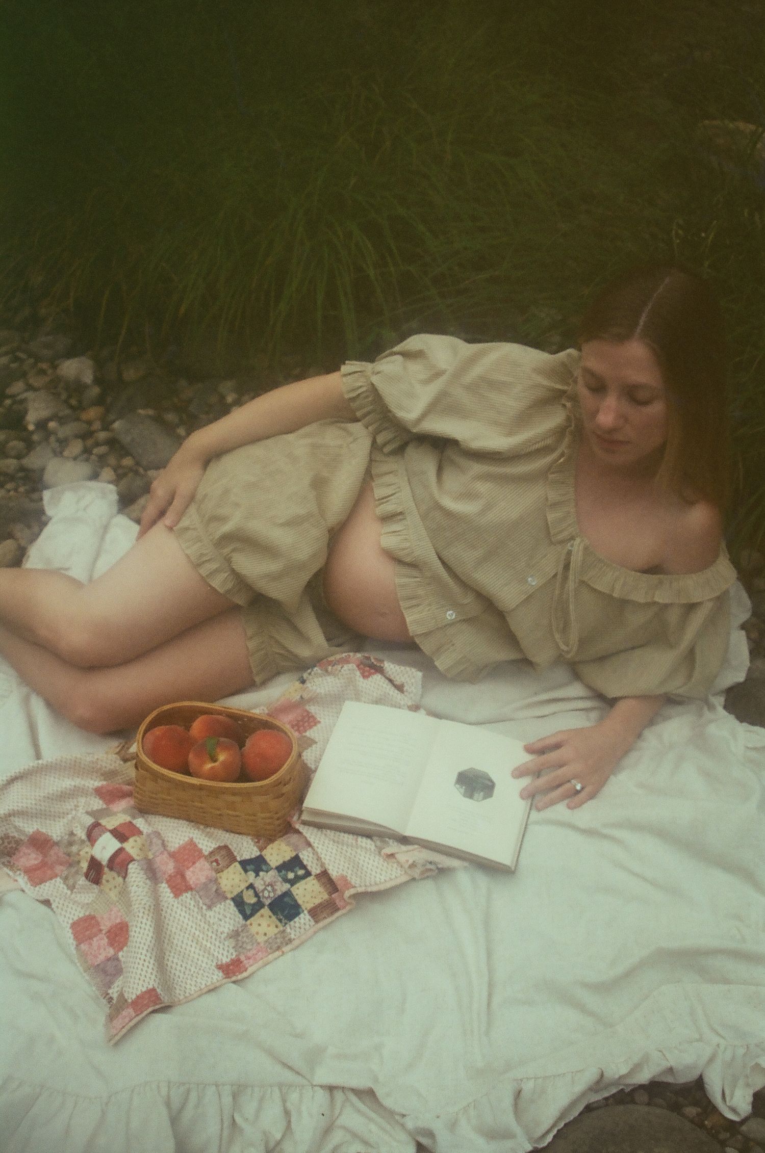 A vintage-style scene shows someone in a light dress reclining on a white blanket with a basket of fruit nearby.