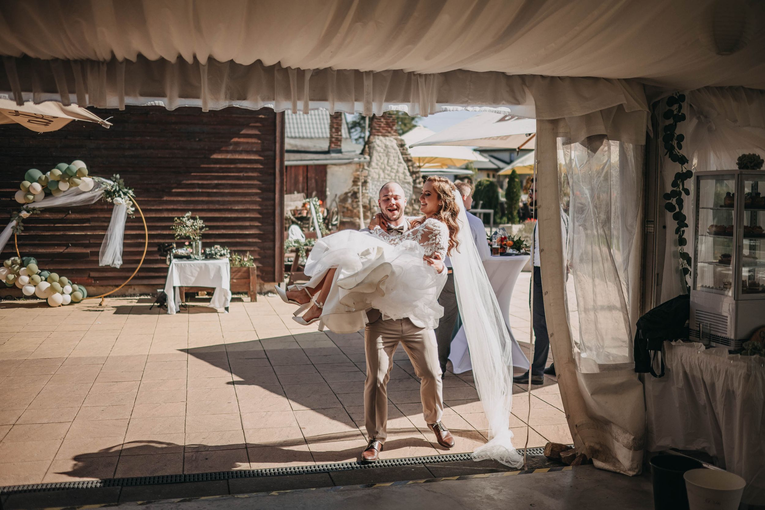 Wedding ceremony setup under white tents with rustic decorations and floral arrangements.