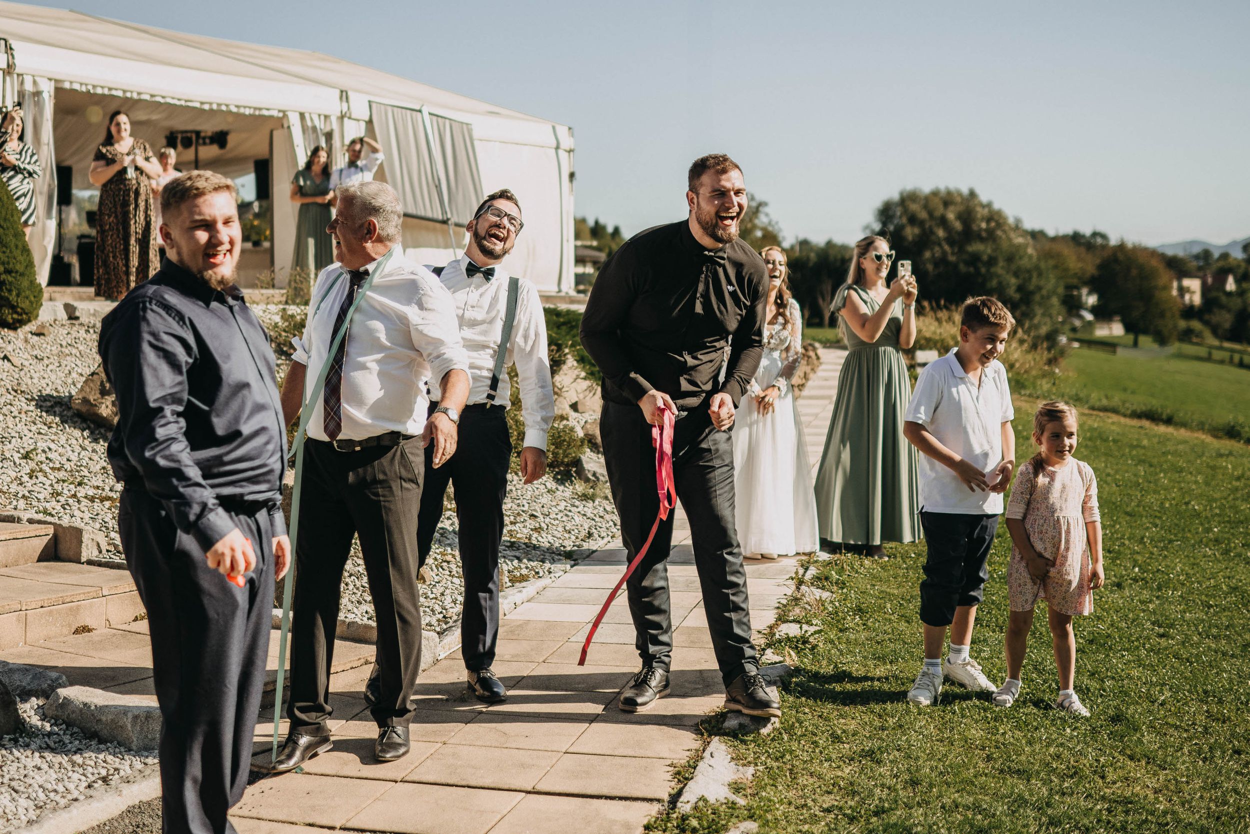 Wedding guests mingling on a grassy lawn outside the reception venue.