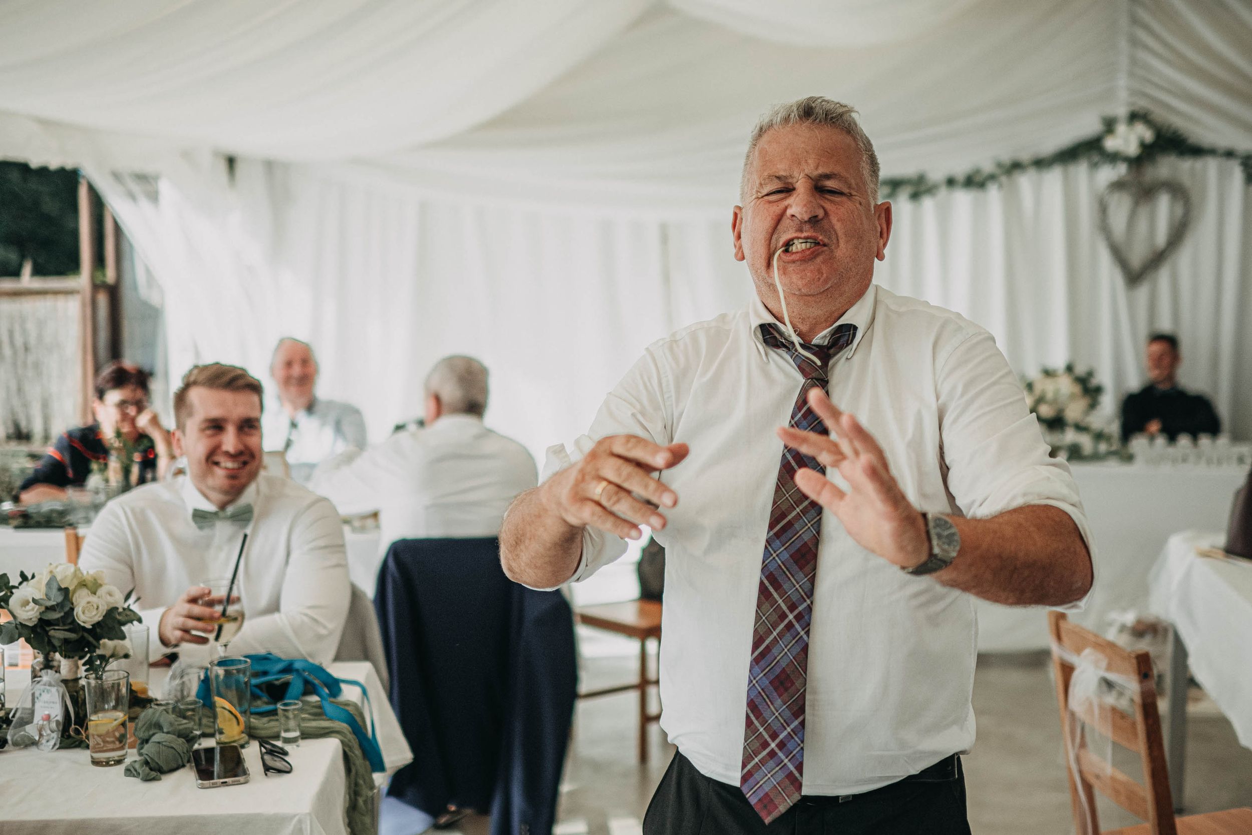 Wedding guests mingling and toasting during an indoor reception celebration.